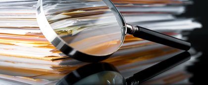 Magnifying Glass Next To Stack Of Files